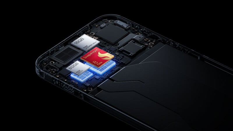 Una vista en primer plano de los componentes internos del teléfono inteligente, destacando el procesador Qualcomm Snapdragon en la placa base, un chip de memoria de 16 GB y un chip de almacenamiento de 512 GB, todo dentro de la carcasa parcialmente transparente del teléfono.