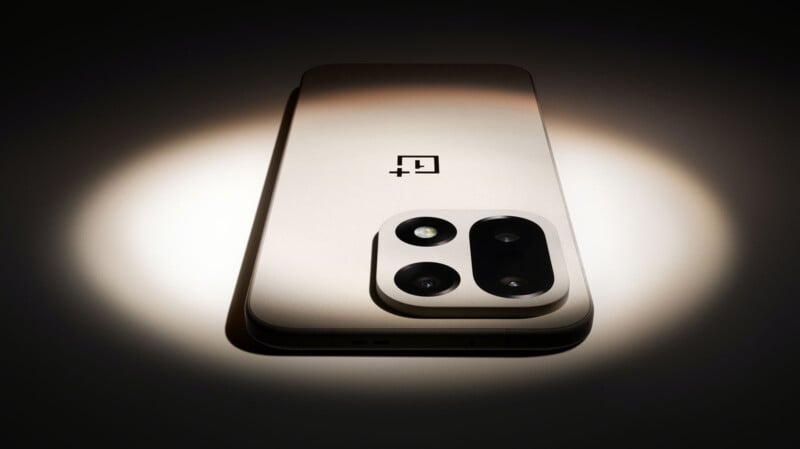 Bajo el foco se muestra un teléfono inteligente metálico con un gran módulo de cámara trasera de doble lente con el logotipo de OnePlus en la parte posterior.
