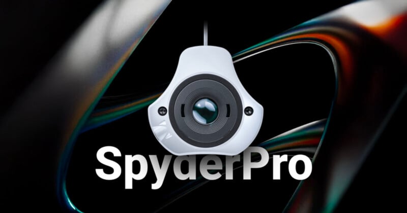 A close-up of a SpyderPro calibration device hanging against a dark, abstract background, with the word “SpyderPro” in bold white text below.