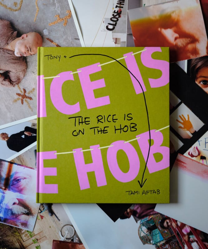 A green book titled "The Rice Is On The Hob" by Tami Aftab lies on top of scattered, colorful photographs. The bold pink cover text dominates, with black handwritten notes and arrows pointing to the title and author.