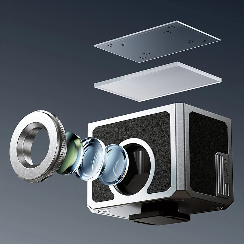 An exploded view of a compact camera shows separated lens elements, a metallic ring, and two flat glass plates, all suspended above and in front of a square camera body against a gradient background.