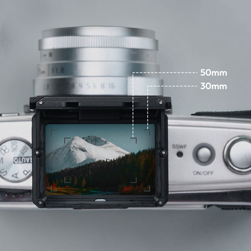 A camera with its LCD screen displaying a landscape of snowy mountains and trees. Dotted lines indicate 50mm and 30mm focal lengths, showing the difference in framing on the screen.
