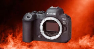 A Canon EOS R6 Mark II mirrorless camera is shown without a lens, set against a dramatic red and orange smoky background.