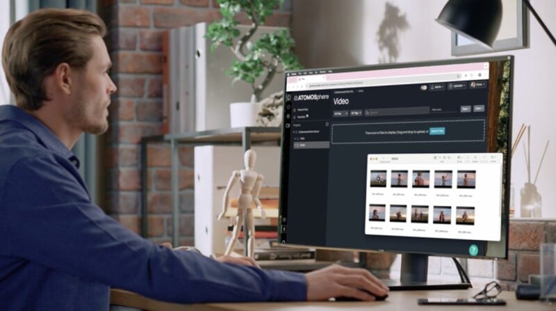 Una persona se sienta en un escritorio y usa una computadora de escritorio con un monitor grande que muestra un proyecto de video y varias miniaturas de imágenes. El espacio de trabajo incluye plantas, maniquíes de madera y libros en estanterías.