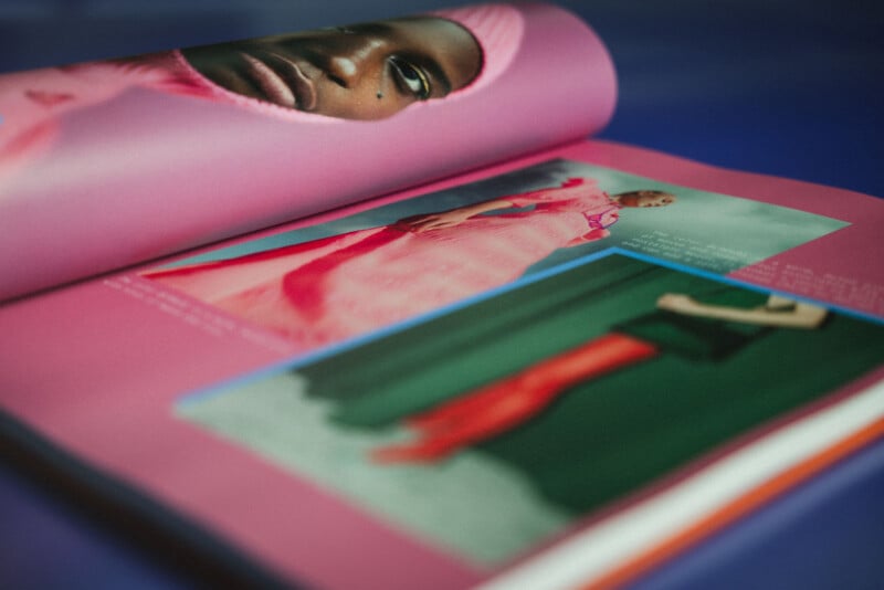 An open fashion magazine shows a close-up portrait of a person in pink and photos of models wearing colorful, stylish outfits against pink and green backgrounds.