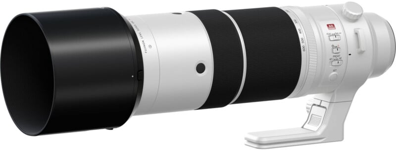 A large white professional telephoto camera lens with a black lens hood, tripod mount, and control switches, designed for high-end photography, isolated on a white background.