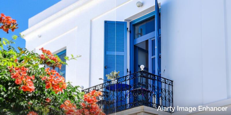 A white building with blue shutters and a balcony, surrounded by vibrant orange flowers. The left half is faded, while the right half is vivid, showing image enhancement. "Aiarty Image Enhancer" is written in the bottom right corner.