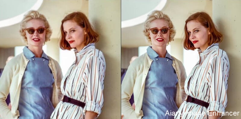 Two women stand side by side, both with short blonde hair and red lipstick, wearing light blue dresses and striped shirts. The left side of the image is blurry, while the right side is clearer and sharper.