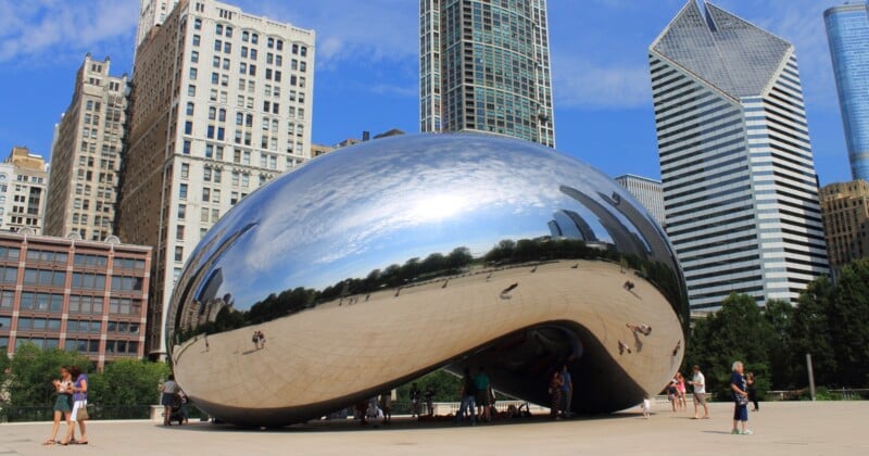 Puerta de las Nubes, también conocida como "frijoles," Gran escultura reflectante en el Millennium Park de Chicago con rascacielos y cielo azul de fondo. La gente se reúne alrededor y debajo de la escultura.