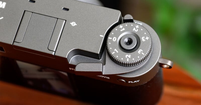 Un primer plano del dial de control en la parte superior de la cámara, grabado con números y símbolos, muestra la muesca detallada y parte del cuerpo de la cámara, incluida la pequeña pantalla al fondo.