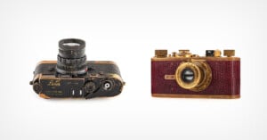 Two vintage cameras are displayed side by side on a white background; the left camera is black with gold accents and the right camera is gold with red textured details.