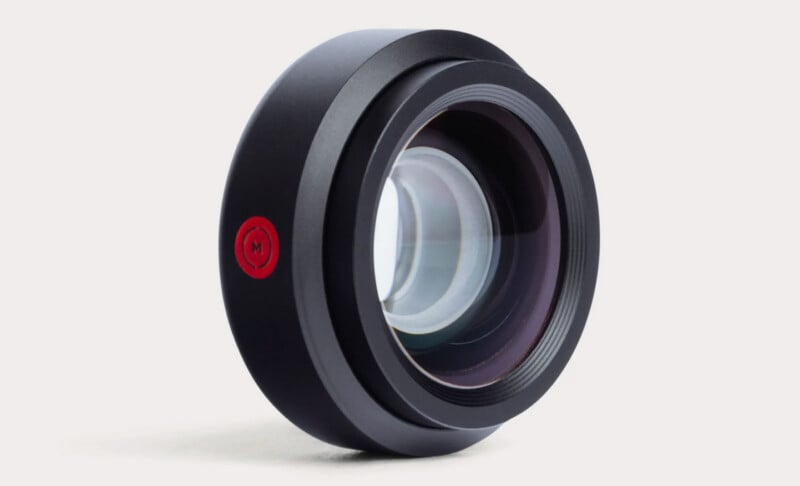 Primer plano de la lente de una cámara negra con un logotipo circular rojo en el lateral, mostrado sobre un fondo blanco liso.