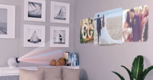 A projector sits on a side table, projecting wedding and couple photos onto a wall above a sofa, which is decorated with framed sailboat pictures and a green plant nearby.