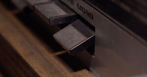 Close-up of buttons on a vintage audio device showing a “MONO” label, with dark, rectangular buttons set against a wooden and metal surface.