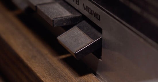 Close-up of buttons on a vintage audio device showing a “MONO” label, with dark, rectangular buttons set against a wooden and metal surface.
