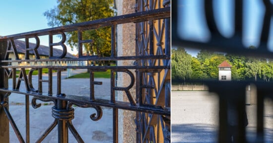 A close-up of an iron gate with the inscription “Arbeit macht frei” and a view through the gate showing a watchtower and trees in the background at a historical site.