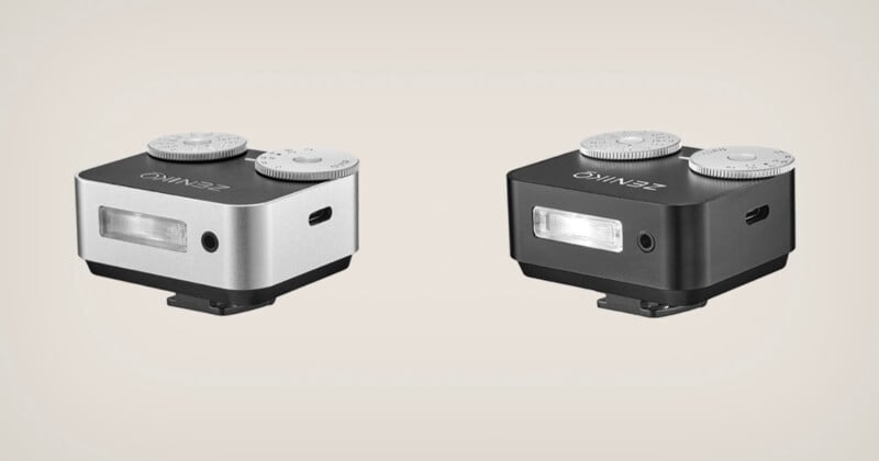 Two compact rectangular camera accessories, one silver and one black, each featuring dials on top, a rectangular light on the front, and a USB port on the side, are shown on a plain light background.
