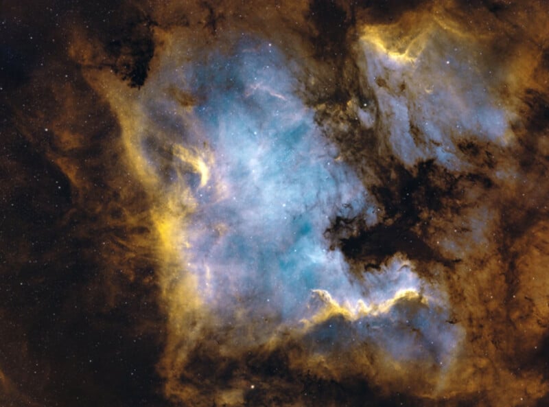 Nebulosa colorida en el espacio con brillantes nubes azules, amarillas y marrones de gas y polvo y estrellas dispersas brillando en la escena cósmica.