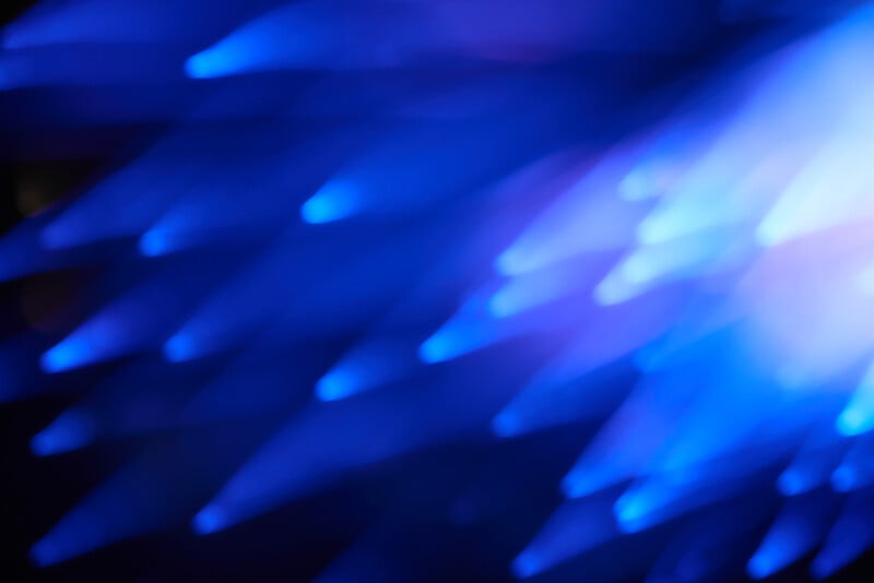 Abstract image featuring streaks of blue and purple light, creating a dynamic, blurred pattern that evokes motion and energy against a dark background.
