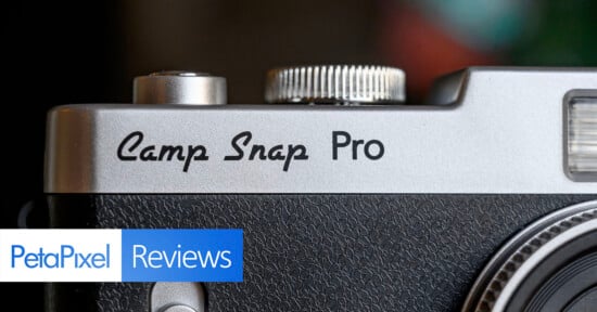 Close-up of a silver and black camera labeled "Camp Snap Pro," with a logo in the corner reading "PetaPixel Reviews." The focus is on the camera's branding and textured surface.