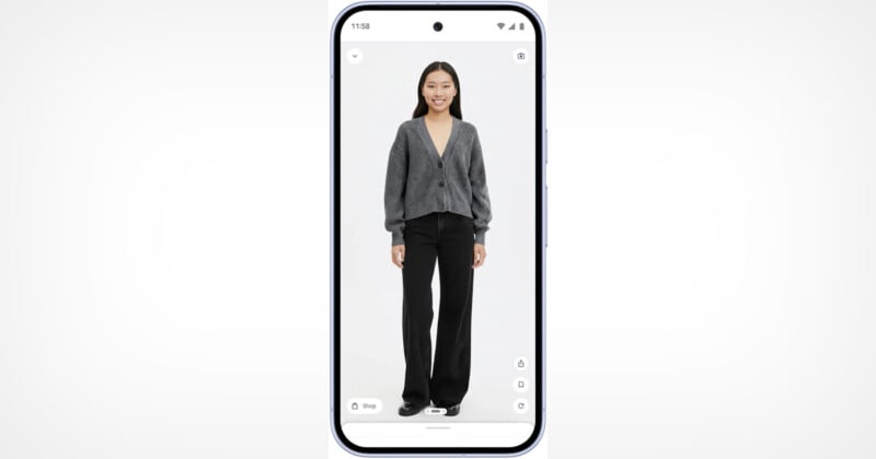 A smartphone displays a smiling woman wearing a gray cardigan and black pants, standing against a plain white background.