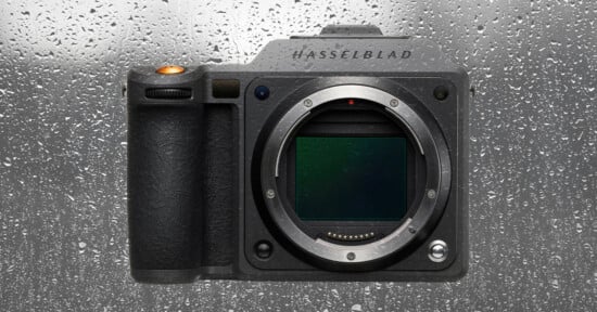 A Hasselblad camera body without a lens is shown against a wet, rain-covered glass background. Water droplets cover the surface behind the camera.