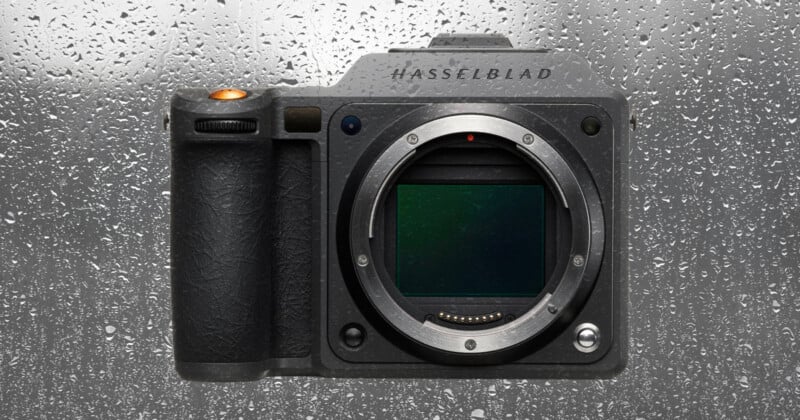 Se muestra el cuerpo de una cámara Hasselblad sin lente sobre un fondo de vidrio húmedo y cubierto de lluvia. Las gotas de agua cubren la superficie detrás de la cámara.