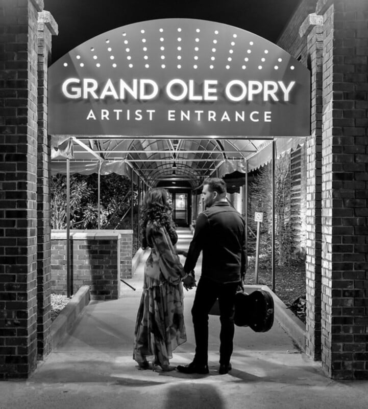 Por la noche, una pareja estaba de la mano bajo el letrero iluminado que decía 