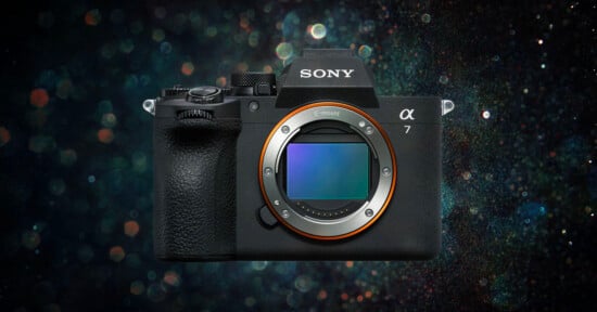 A Sony Alpha 7 mirrorless camera with no lens attached, showing the full-frame sensor, against a dark, bokeh-filled background.