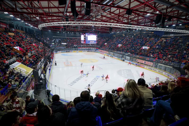 El gran estadio cubierto de hockey sobre hielo estaba lleno de espectadores. Dos equipos, un equipo rojo y un equipo blanco, juegan sobre el hielo. El marcador se iluminó y las brillantes luces de la arena iluminaron la pista y la multitud.