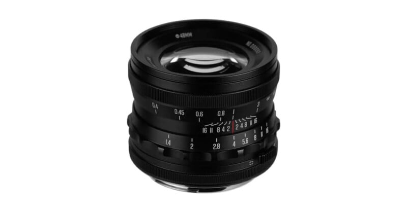 A black camera lens with manual focus and aperture rings, marked with numbers for distance and f-stops, is shown on a white background.