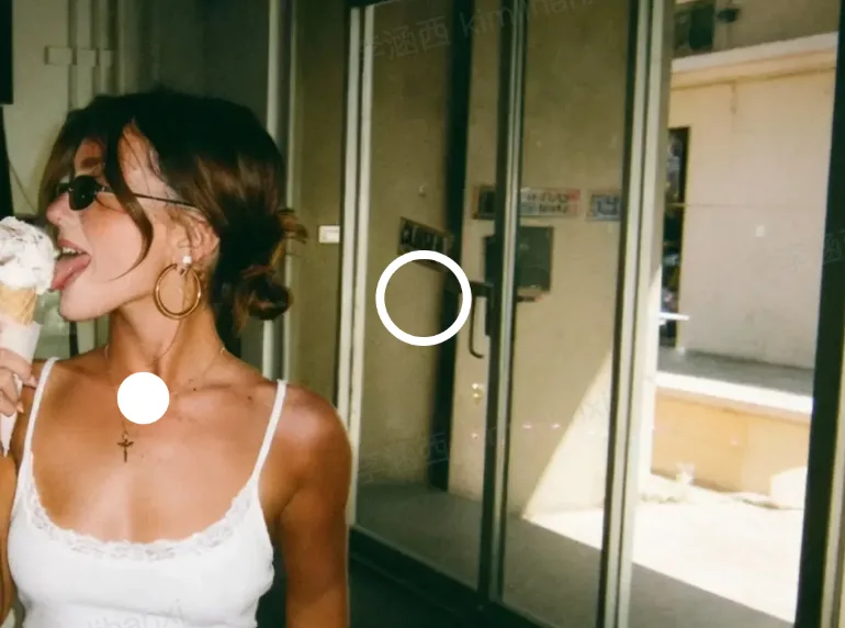 A woman wearing sunglasses and hoop earrings is enjoying an ice cream cone outside, with glass doors and a building in the background.