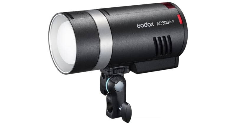 Flash estroboscópico Godox AD300Pro Studio en color negro y plateado con difusor frontal redondo, ranuras de ventilación y soporte de montaje sobre fondo blanco.