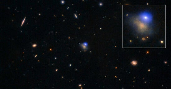 A deep space image showing numerous galaxies and stars scattered across a dark background, with an inset zoom highlighting a bright blue glowing area within a specific galaxy.