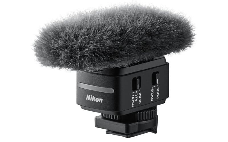 El micrófono Nikon con un suave parabrisas gris se asienta sobre una base de montaje negra, con interruptores etiquetados para configuraciones de audio.