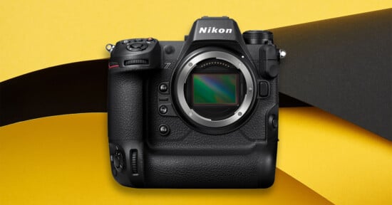 A Nikon mirrorless camera body without a lens is displayed against a yellow and black abstract background.