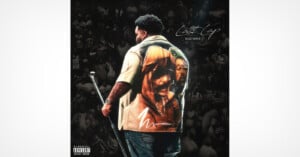 A man stands on stage holding a microphone, wearing a shirt with a large image of a person's face on the back. The background shows a crowd in grayscale. Text reads "Nostalgia Rod Wave.