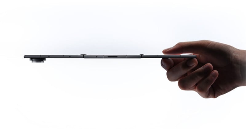 Una mano sostiene el borde de una delgada tableta negra horizontalmente contra un fondo blanco, enfatizando el perfil delgado del dispositivo y la protuberancia elevada de la cámara.