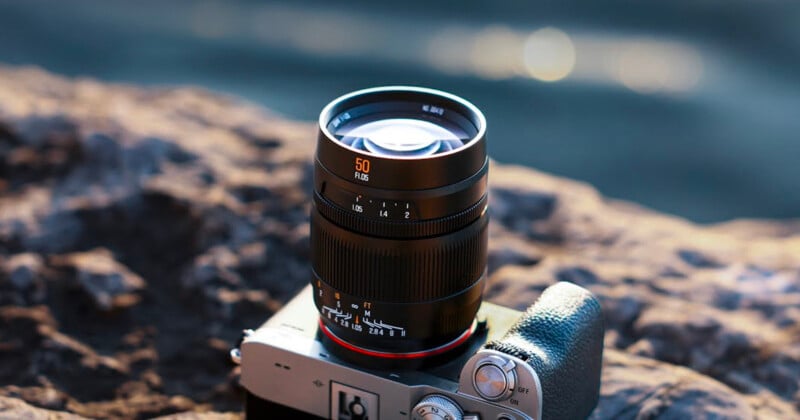 Primer plano de una cámara con lente de 50 mm colocada sobre una superficie rocosa al aire libre con luz solar creando un suave efecto bokeh sobre un fondo borroso.