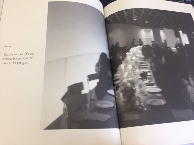 A black-and-white, out-of-focus photo in a book shows a long dinner table with people seated around it. Text on the left page reads: “dinner. i like this picture - it’s out of focus but you can tell there’s a lot going on.”.