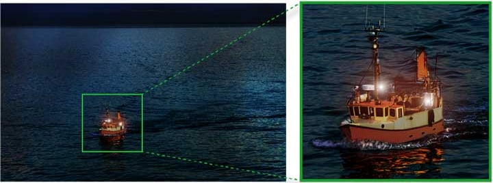 A boat with bright lights moves across dark water at night. A zoomed-in section on the right highlights the illuminated details of the boat’s deck and structure as it creates a wake on the water.