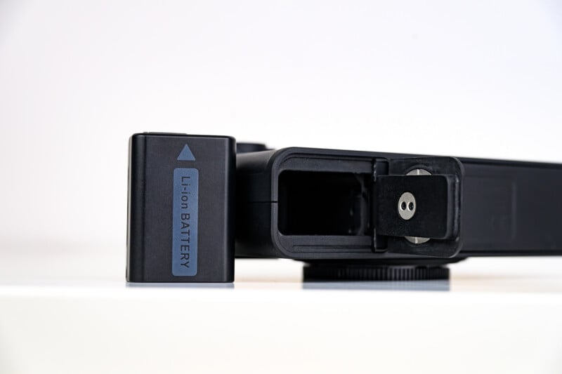 A close-up photo of a black Li-ion battery partially removed from a battery compartment of an electronic device, shown on a white surface with a plain background.