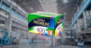 A green and blue box of Superia Premium 400 film with "36 exposures" written on the front, floating against a blurred industrial warehouse background.