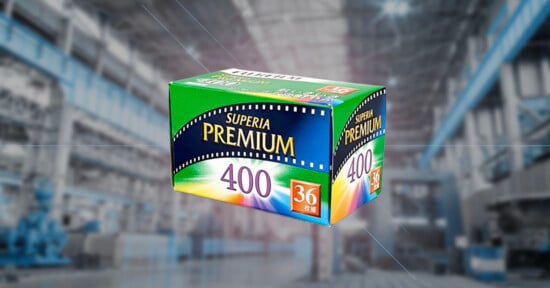 A green and blue box of Superia Premium 400 film with "36 exposures" written on the front, floating against a blurred industrial warehouse background.