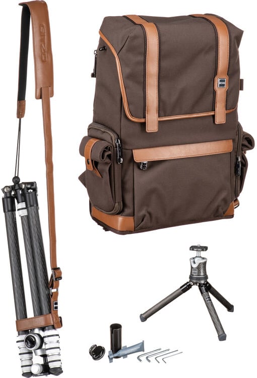 A brown and tan camera backpack with leather accents, a folded tripod with a carrying strap, a small tabletop tripod, and various small accessories including keys and mounting parts are displayed on a white background.