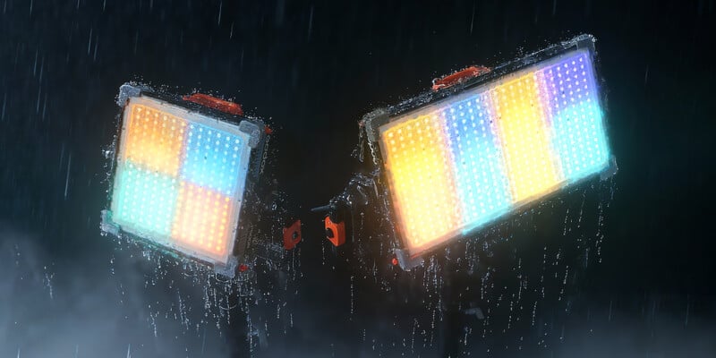 Two rectangular LED lights with colorful panels shine brightly in the rain, droplets visible on their surfaces and in the air, against a dark background.