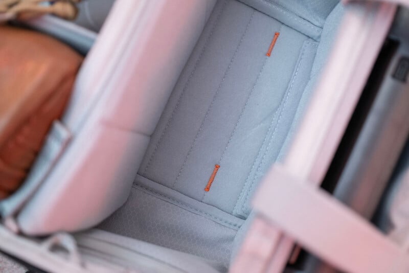 Close-up view of the interior of a light gray car seat, showing padded cushioning with subtle orange stitching details and textured side panels.