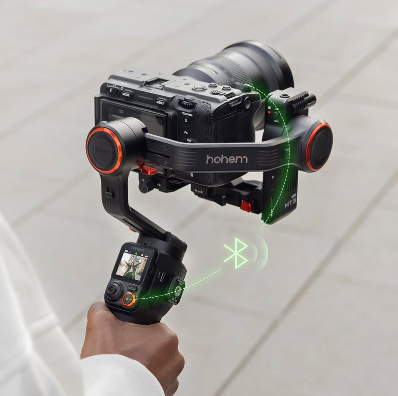 A person holds a Hohem brand handheld camera stabilizer with a mounted camera, displaying smooth motion and Bluetooth connectivity indicated by green graphics.