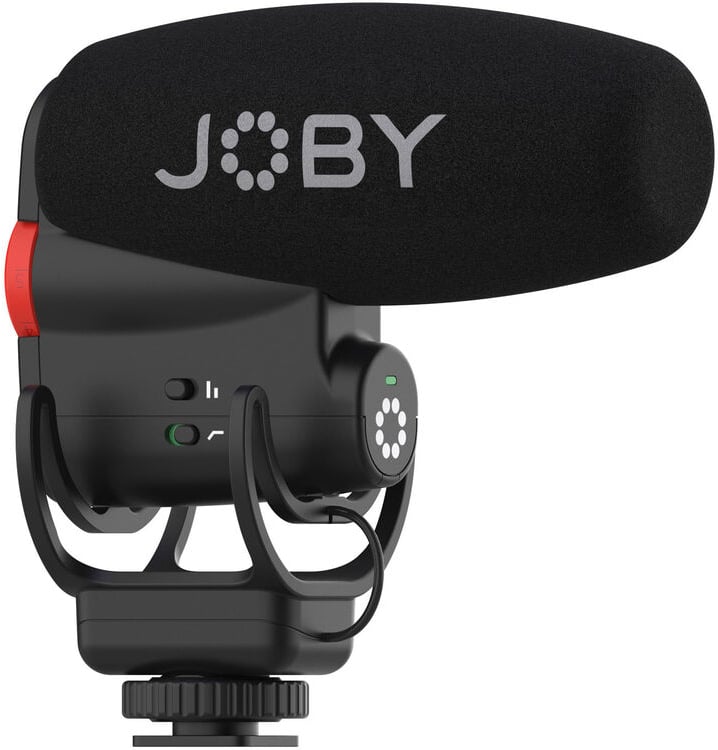 Close-up of a JOBY-branded black shotgun microphone with a foam windscreen, mounted on a shock mount with visible control buttons and an attachment for connecting to a camera or tripod.