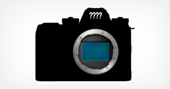 Silhouette of a mirrorless camera with a visible image sensor where the lens would attach, and four question marks above, suggesting mystery or an unknown camera model.